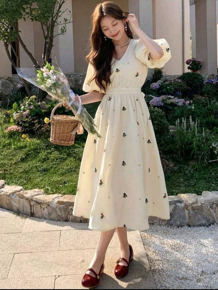 Woman in a cream floral embroidered midi dress with puff sleeves and a basket bag outdoors. Perfect inspiration for vintage summer dresses, cottagecore outfits, and breezy warm-weather fashion.